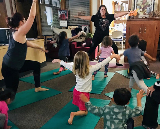 Students in College of San Mateo’s yoga teacher training certificate program lead kids in yoga poses at CSM’s Child Development Center